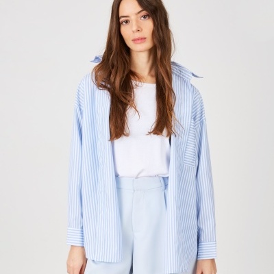 Mulher com camisa às riscas e calções azuis claros em fundo branco