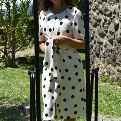 Vestido midi branco com bolinhas pretas refletido em espelho de pé em jardim