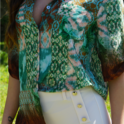 Blusa colorida com padrão geométrico e saia/calça branca com botões dourados