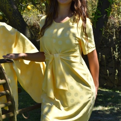 Mulher a usar vestido amarelo de bolinhas num jardim