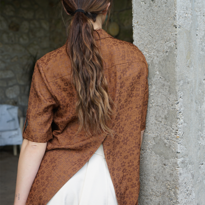 Camisa castanha de manga curta com padrão floral e corte traseiro dividido, vista de costas