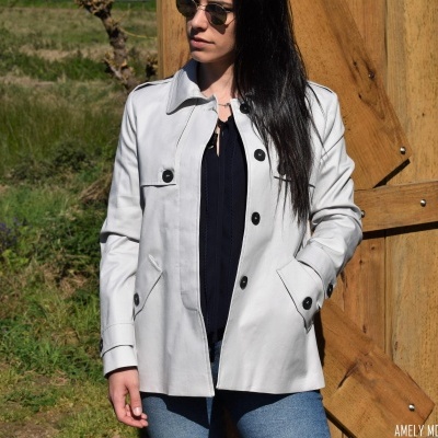 Casaco branco com botões pretos usado por mulher ao ar livre