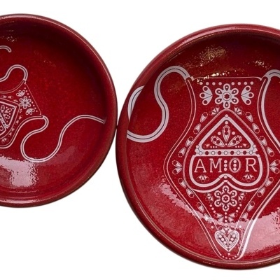 Dois pratos vermelhos de cerâmica com decoração branca e palavra AMOR
