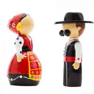 Duas figuras tradicionais em madeira vestidas com trajes típicos, uma mulher com vestido vermelho e avental floral, e um homem com traje preto e chapéu.