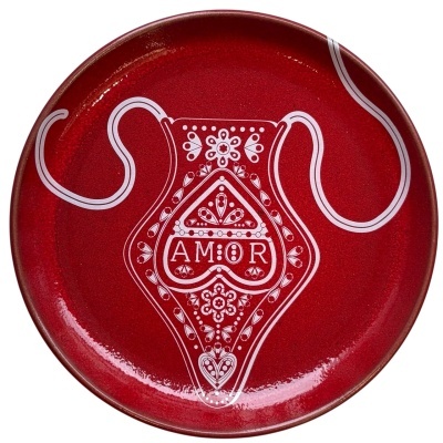 Prato cerâmico vermelho decorado com jarro branco e palavra AMOR