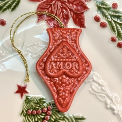 Enfeite decorativo vermelho com palavra AMOR e cordão dourado com pendente estrela vermelha.