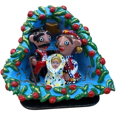 Presépio colorido com três figuras em cerâmica dentro de moldura azul com decoração em verde e vermelho