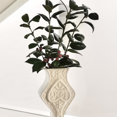 Vaso cerâmico branco com relevo AMOR e ramo artificial de folhas verdes e bagas cor-de-rosa