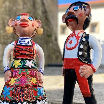 Figuras decorativas de casal com trajes tradicionais coloridos e expressões caricatas