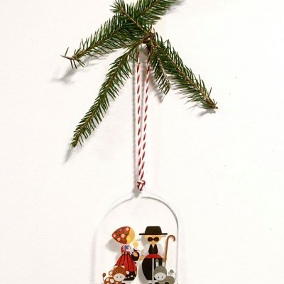 Ornamento de Natal com figuras de madeira pendurado em ramo de pinheiro