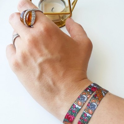 Mão com anéis e pulseira colorida ao lado de castiçal dourado com vela