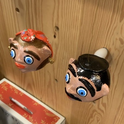 Ornamentos pendurados representando cabeças caricaturais com olhos grandes azuis e detalhes coloridos.