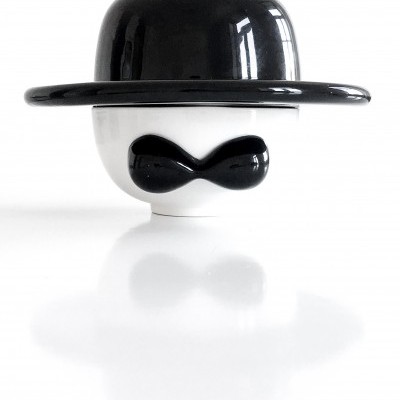 Figura branca com chapéu e bigode pretos brilhantes sobre fundo branco