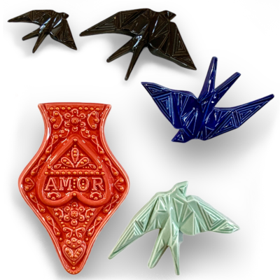 Peças decorativas de cerâmica incluindo andorinhas e objeto vermelho com a palavra AMOR