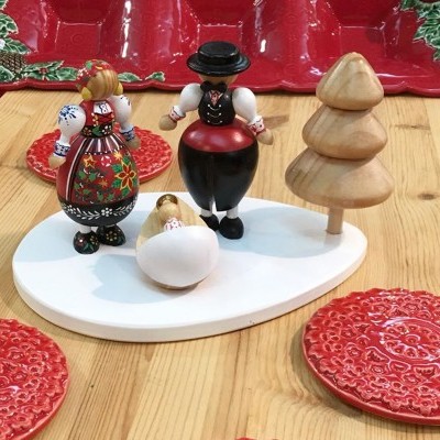 Figuras decorativas em madeira com roupa tradicional colorida, base branca oval, árvore de madeira e pratos vermelhos texturizados