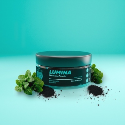 Frasco preto de pó branqueador Lumina com folhas verdes e pó preto ao redor
