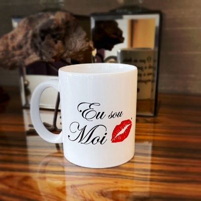 Caneca branca com texto e lábio vermelho em superfície de madeira