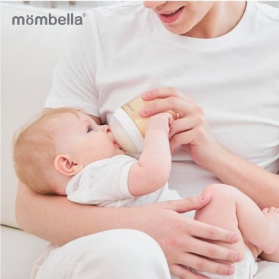 Adulto com t-shirt branca a alimentar bebé com biberão