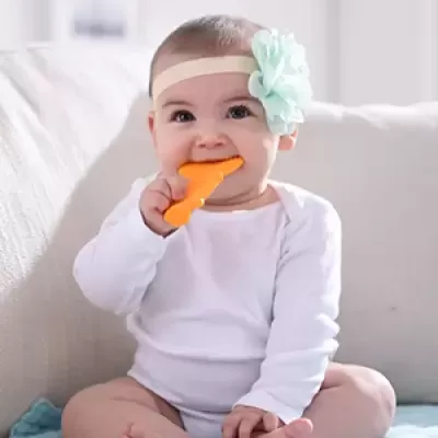 Bebé com faixa de cabeça e brinquedo de silicone laranja a morder