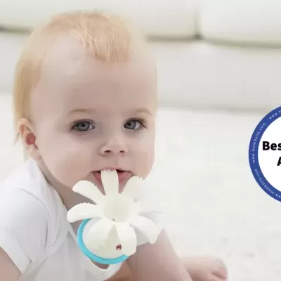 Bebé a segurar brinquedo branco em forma de flor com argola azul