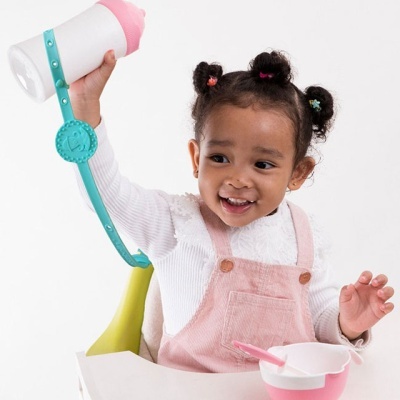 menina com macacão rosa e camisola branca segurando garrafa com tampa rosa