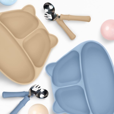 Pratos de silicone divididos e talheres para crianças nas cores bege e azul com formato de urso.