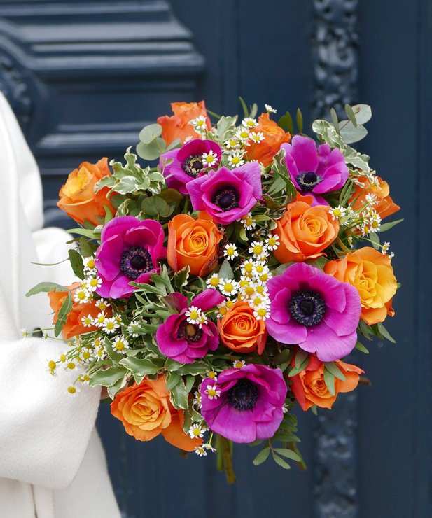 Buquê colorido de flores laranja, amarelas e roxas com folhagem verde