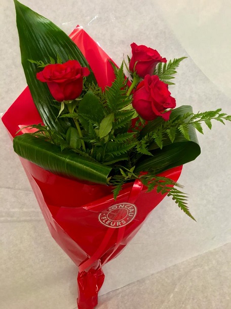Buquê de três rosas vermelhas com folhas verdes em papel vermelho