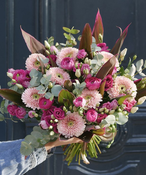 Buquê colorido de flores rosas e verdes com folhas castanhas numa mão