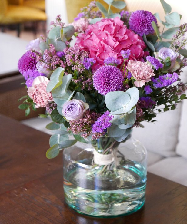 Arranjo floral em jarra de vidro sobre mesa de madeira