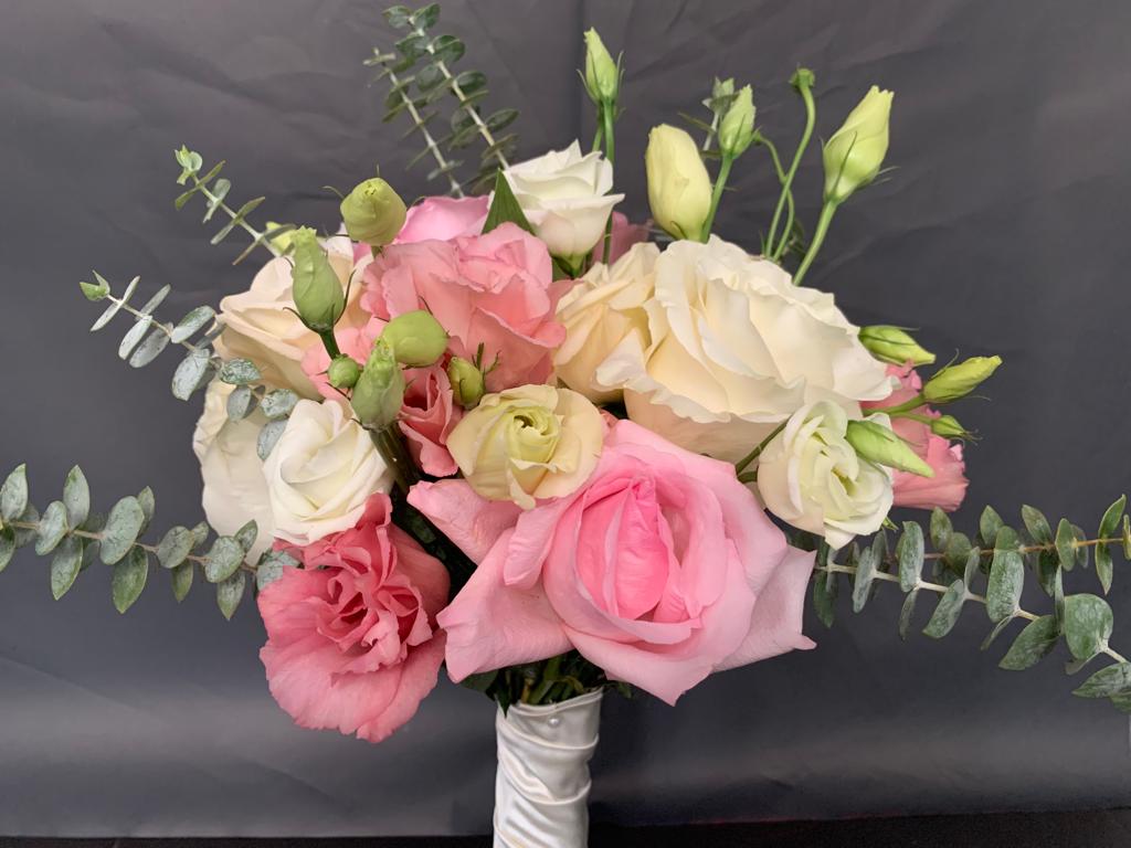 Bouquet de rosas cor de rosa e brancas com folhas verdes e fita branca