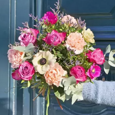 Buquê colorido de flores variadas com fundo de porta azul.