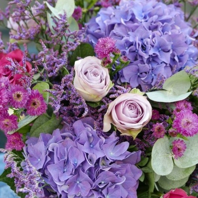 Buquê colorido de hortênsias lilás, rosas rosas e flores pequenas lilases com folhagem verde