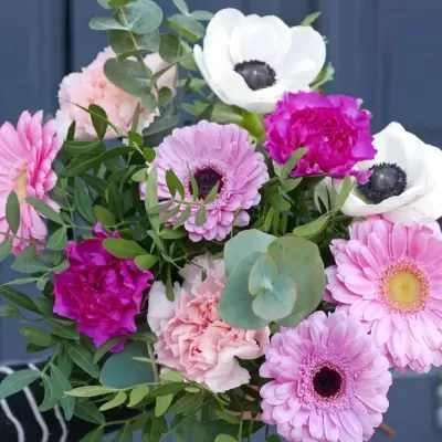 Bouquet colorido de flores com folhas verdes em fundo azul