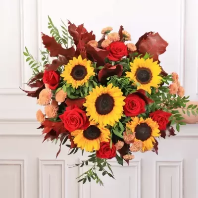 Arranjo floral com girassóis, rosas vermelhas e folhas secas castanhas