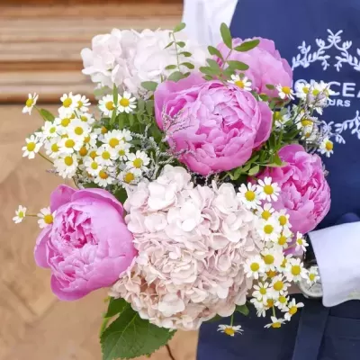 Ramo de flores coloridas segurado por pessoa com bata azul