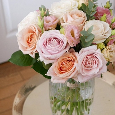 Bouquet de rosas em vaso de vidro sobre mesa clara.