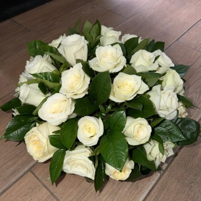 Bouquet de rosas brancas e folhas verdes sobre chão de madeira