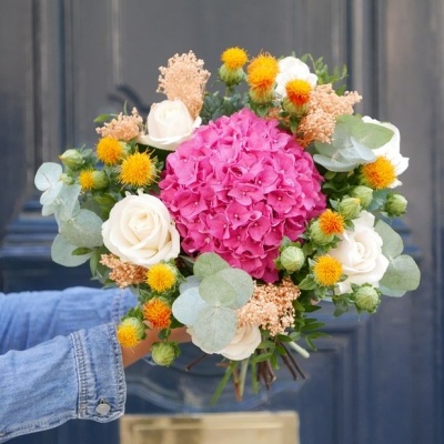 Ramo de flores colorido segurado em frente a uma porta azul escura