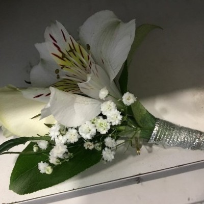Buquê de flores brancas com fita prateada numa superfície clara