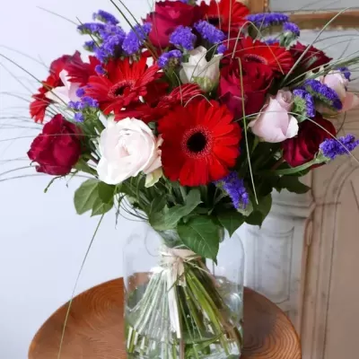 Arranjo floral colorido em jarro de vidro sobre mesa de madeira