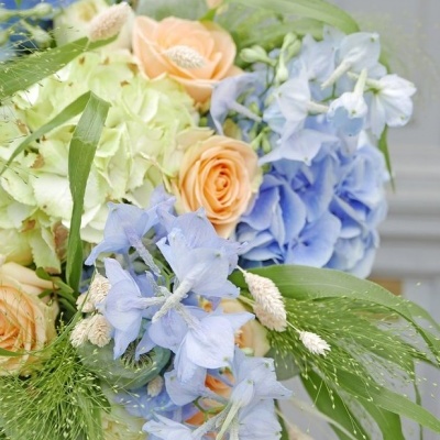 Buquê de flores com rosas pêssego, flores azuis, hortênsias verdes e folhagens