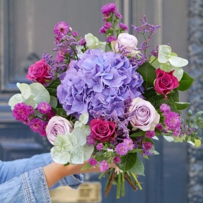Ramo de flores coloridas seguro à frente de porta azul