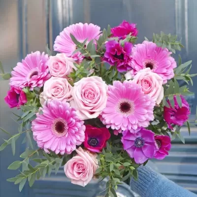 Bouquet de flores cor-de-rosa e verde segurado por mão com manga azul