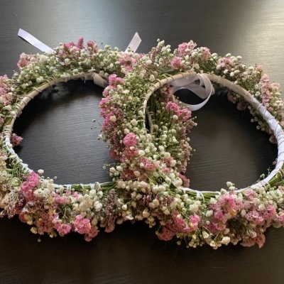 Duas coroas florais com flores brancas e cor-de-rosa sobre superfície preta