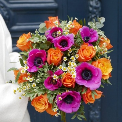 Buquê colorido de flores laranja, amarelas e roxas com folhagem verde