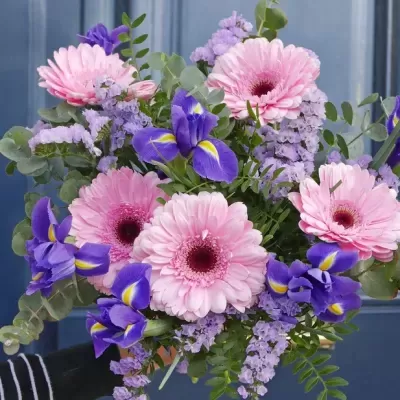 Bouquet colorido com flores cor-de-rosa, roxas e lilases em fundo azul