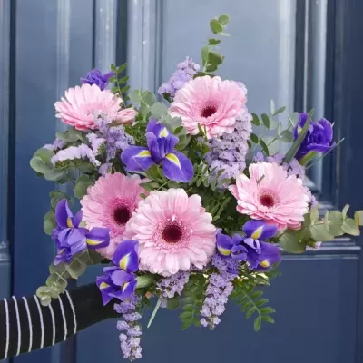 Ramo de flores rosa e roxas com folhagem verde em fundo de porta azul