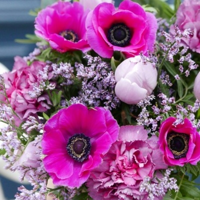 Bouquet cor de rosa e lilás com flores e folhagem verde.