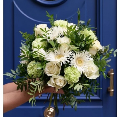 Bouquet de flores brancas e verdes com folhagem junto a uma porta azul